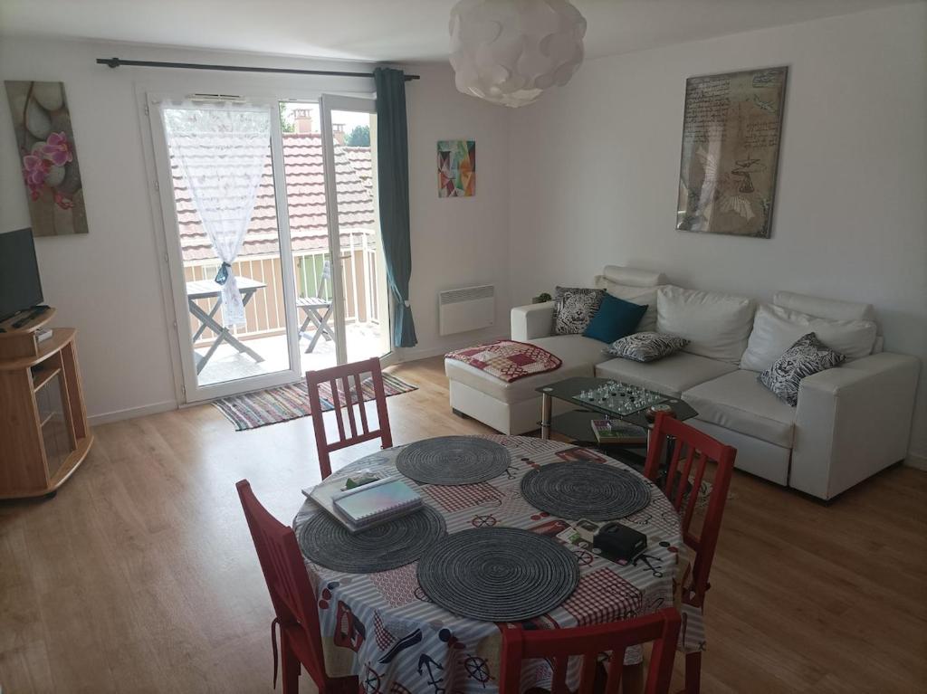 una sala de estar con una mesa y un sofá en grand appartement dans résidence sécurisée, en Beuzeville