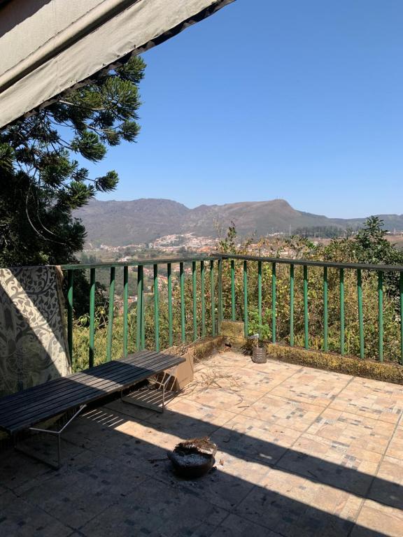 a patio with a bench and a fence with mountains in the background at Suíte vista maravilhosa in Ouro Preto