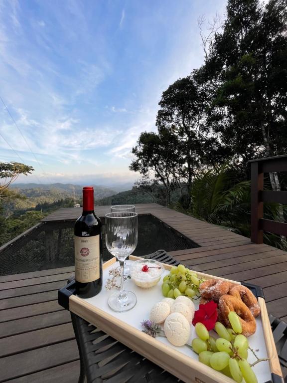 a plate of food and a bottle of wine on a table at Recanto do Príncipe, privacidade, paz e contato Com a natureza in Marechal Floriano