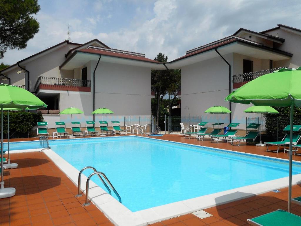 ein Pool mit Stühlen und Sonnenschirmen neben einem Hotel in der Unterkunft Casa Bianca Village Apartments in Lignano Sabbiadoro