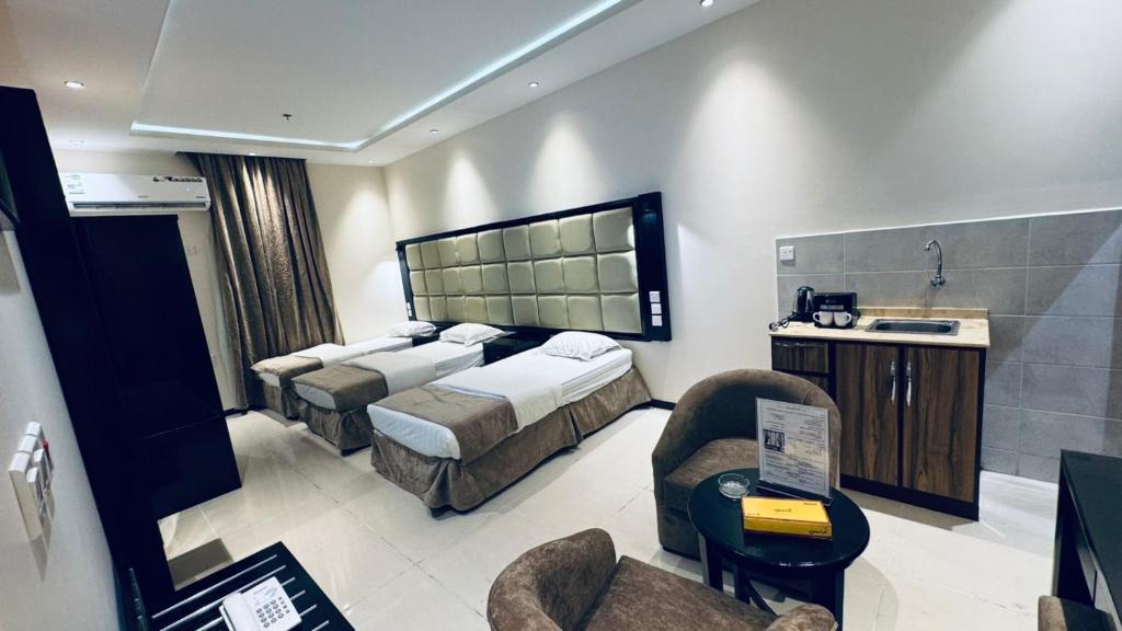 a hotel room with two beds and a chair at شقق دار الفرسان المخدومة in Quai