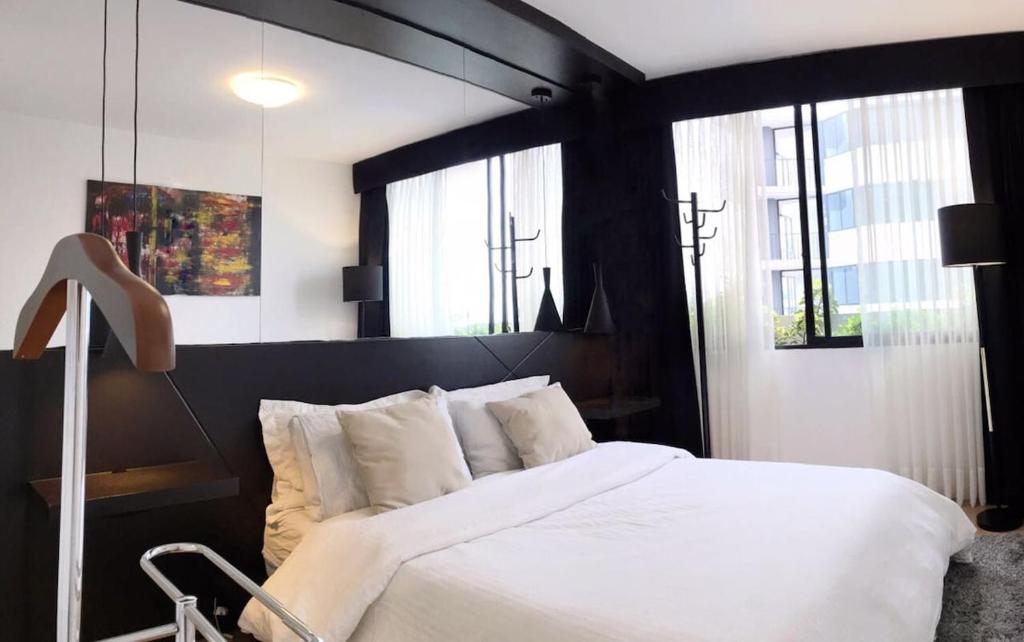 a bedroom with a bed with white sheets and windows at Cozy, Elegant & Comfortable Apartment in Lima in Lima