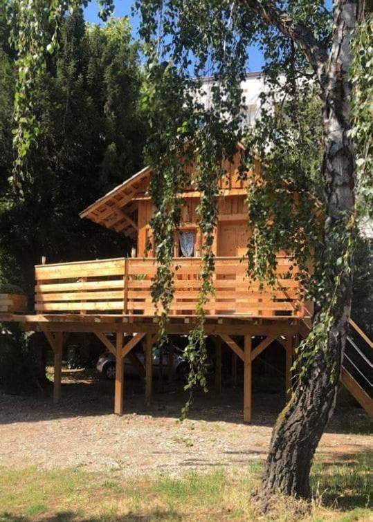 a tree house with a bench in front of it at chalet dans la ville in Sélestat