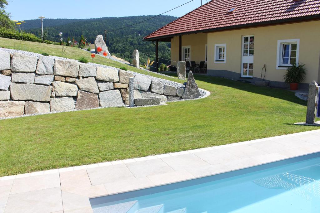a retaining wall next to a house with a swimming pool at Appartement Johanna in Schwarzenberg am Bohmerwald