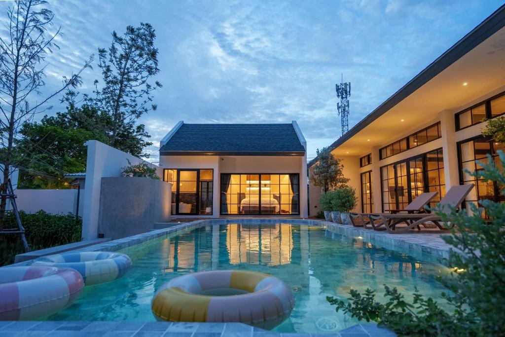 ein Haus mit einem Swimmingpool vor einem Gebäude in der Unterkunft Hestiana in Ban Hua Khao Sammuk