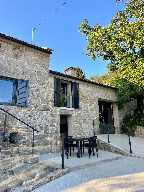 a table and chairs in front of a stone building at Casa rural Reibón in Moaña