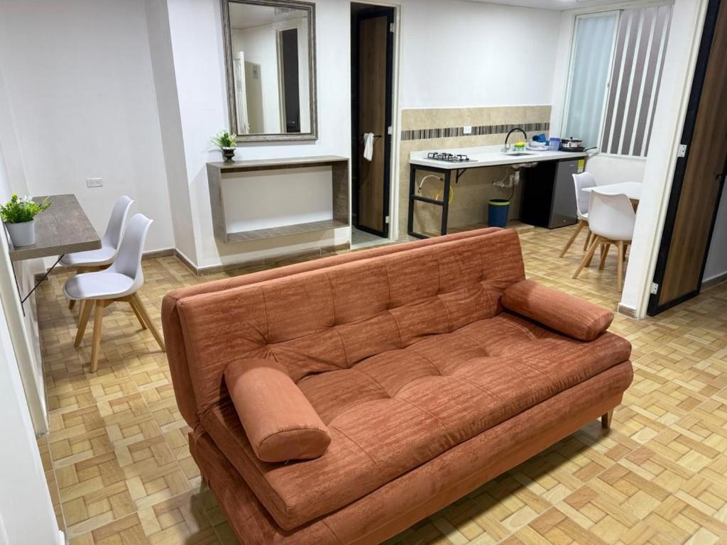 een woonkamer met een bruine bank en een keuken bij Hospedarte Cali Sur in Cali