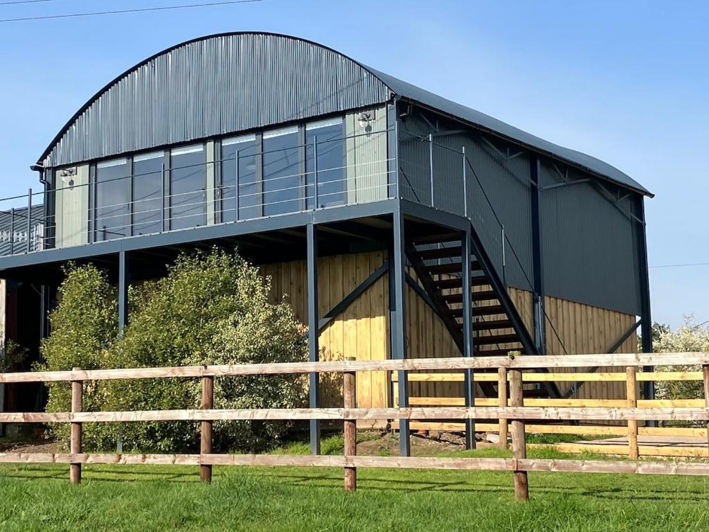 a black barn with a wooden fence in front of it at Stunning Contemporary Dutch Barn Conversion in Whixall