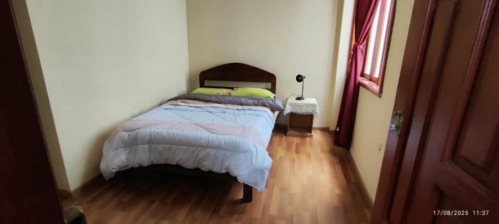 ein kleines Schlafzimmer mit einem Bett und einem Holzboden in der Unterkunft Departamento El Mirador Concax in Los Baños del Inca