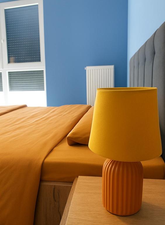 żółta lampa stojąca na stole obok łóżka w obiekcie Orange Apartment w mieście Prizren
