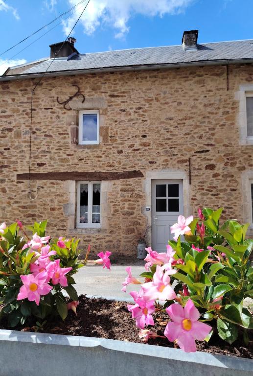 a brick house with pink flowers in front of it at La Maison des Rosiers in Manhac