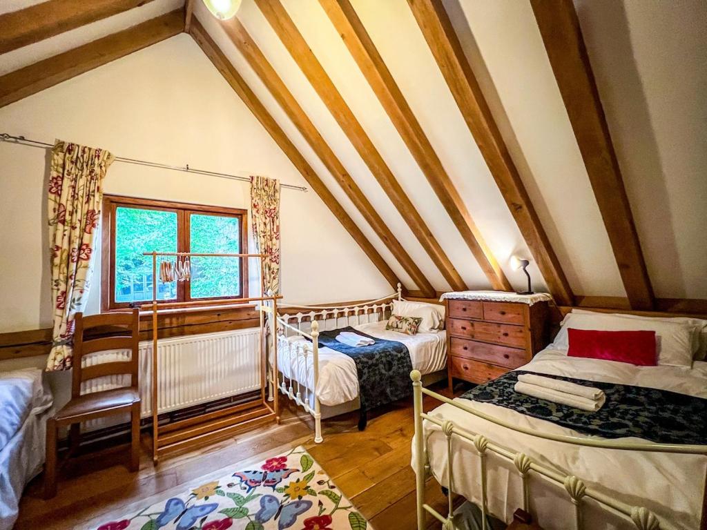 a attic room with two beds and a window at Nightingale Barn - Stunning & Huge in Etchingham