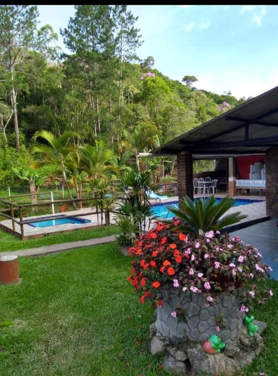 a yard with flowers and a swimming pool at Sítio Isolina Piscina, Campo e Lago in Juquitiba