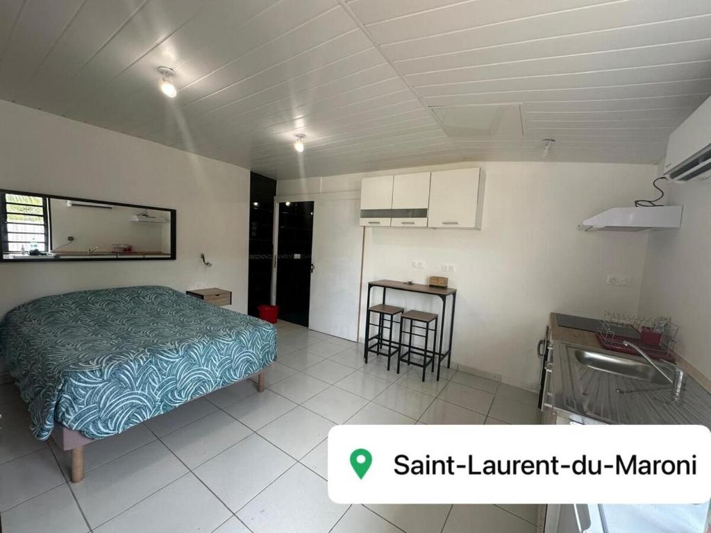 ein Schlafzimmer mit Bett und Tisch und eine Küche in der Unterkunft Studio RIO in Roche Cabrit