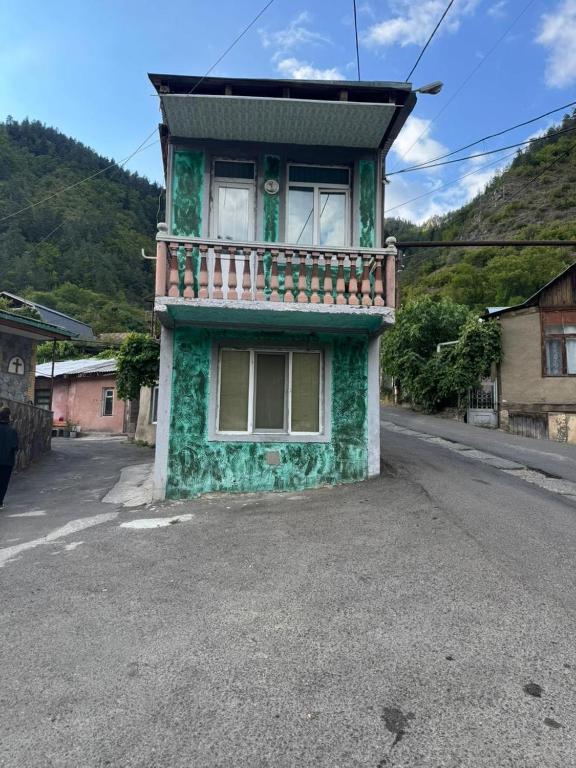 a green building with a balcony on a street at Borjomi Cozy Cottage in Borjomi