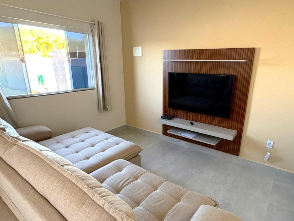 un soggiorno con divano e TV a schermo piatto di Oasis das Dunas a Cabo Frio
