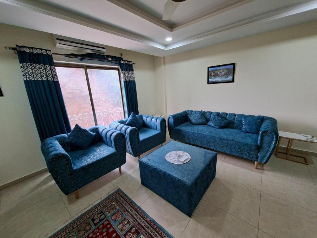 a living room with blue furniture and a large window at Private 1 BHK Suite - Islamabad, Bahria Town in Rawalpindi