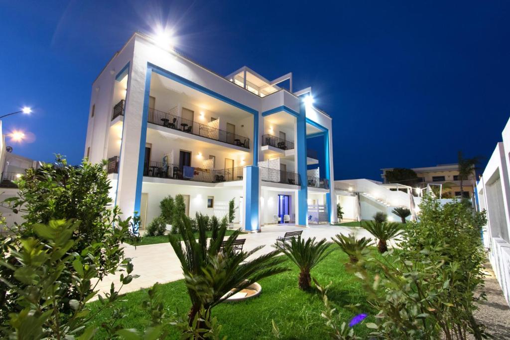 ein großes weißes Gebäude mit blauen Akzenten in der Nacht in der Unterkunft Gigli Hotel Salento in Marina di Pescoluse