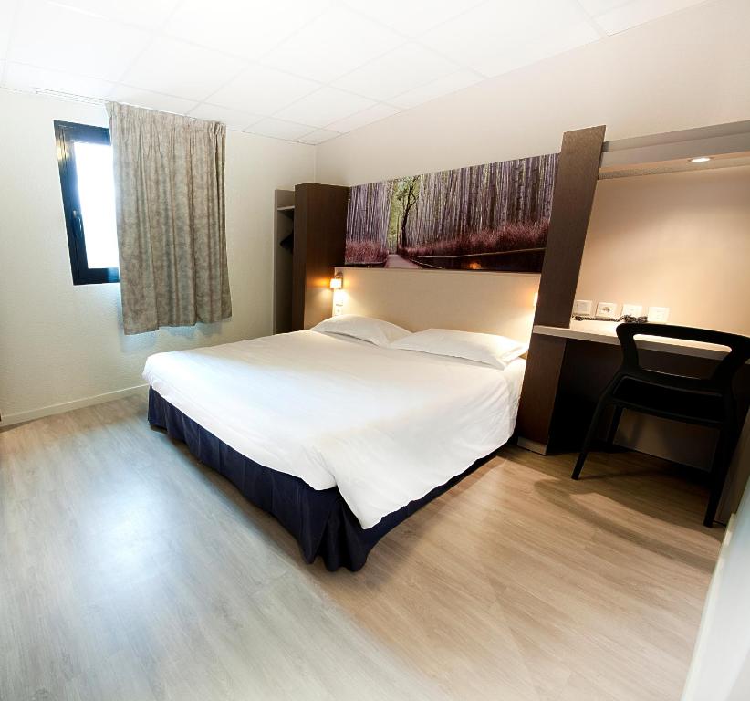 - une chambre avec un grand lit blanc et une chaise dans l'établissement The Originals City, Hôtel Clermont-Ferrand Sud Aubière, à Aubière
