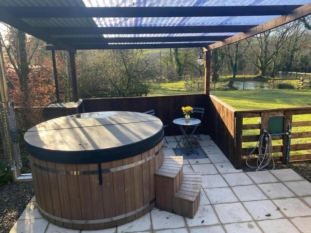 a wooden deck with a hot tub and a pergola at Hendre Glamping- Caravan Bryngwyn in Boncath