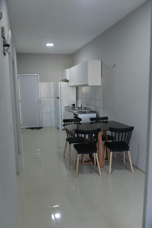 a kitchen with a table and chairs and a refrigerator at Suítes House Cacique in Cruz