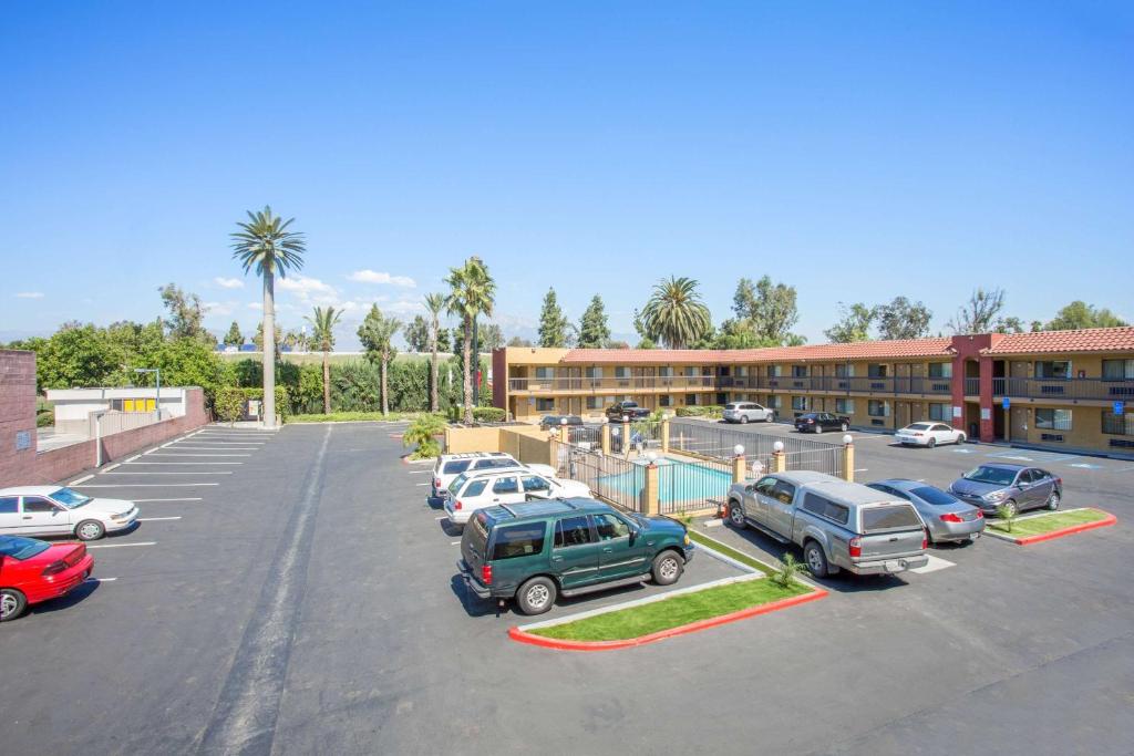 a parking lot with cars parked in front of a building at Hotel Seville - Ontario Airport/Chino in Ontario