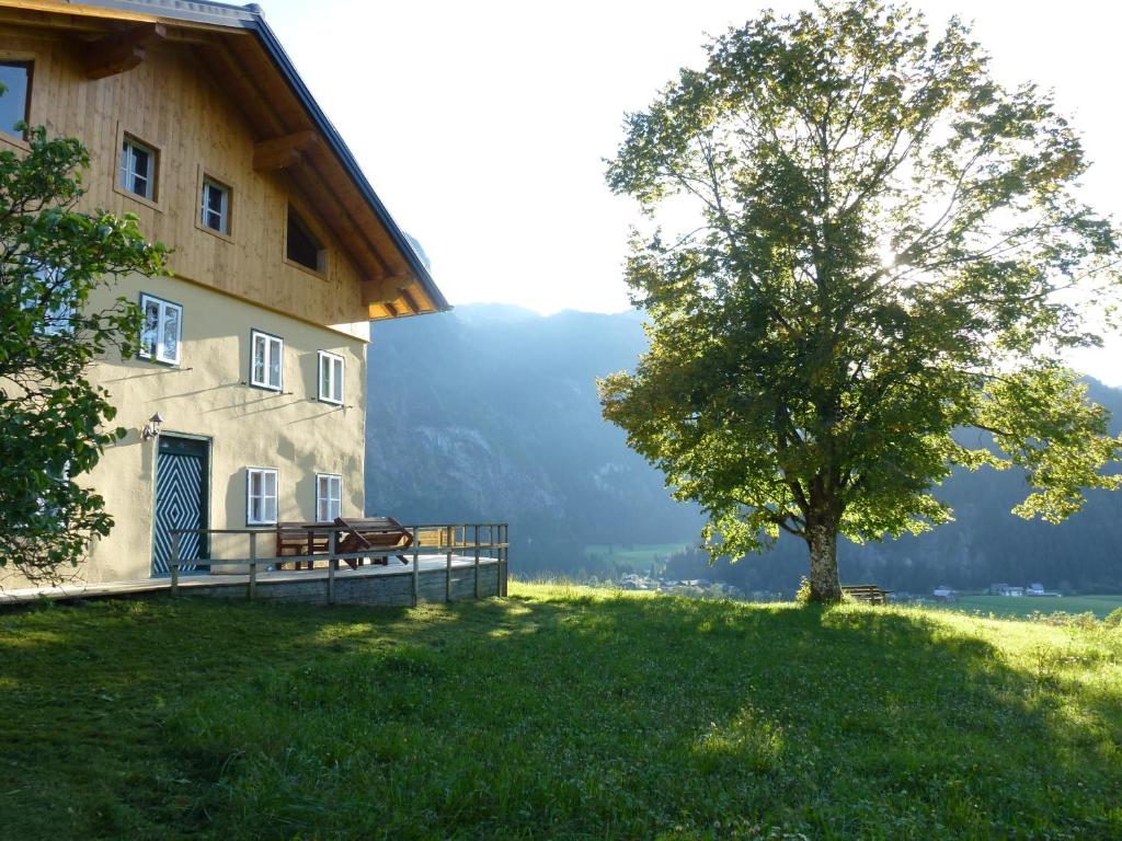 un edificio con un banco y un árbol al lado en Ferienwohnung Bauernhaus Untermoas, en Abtenau