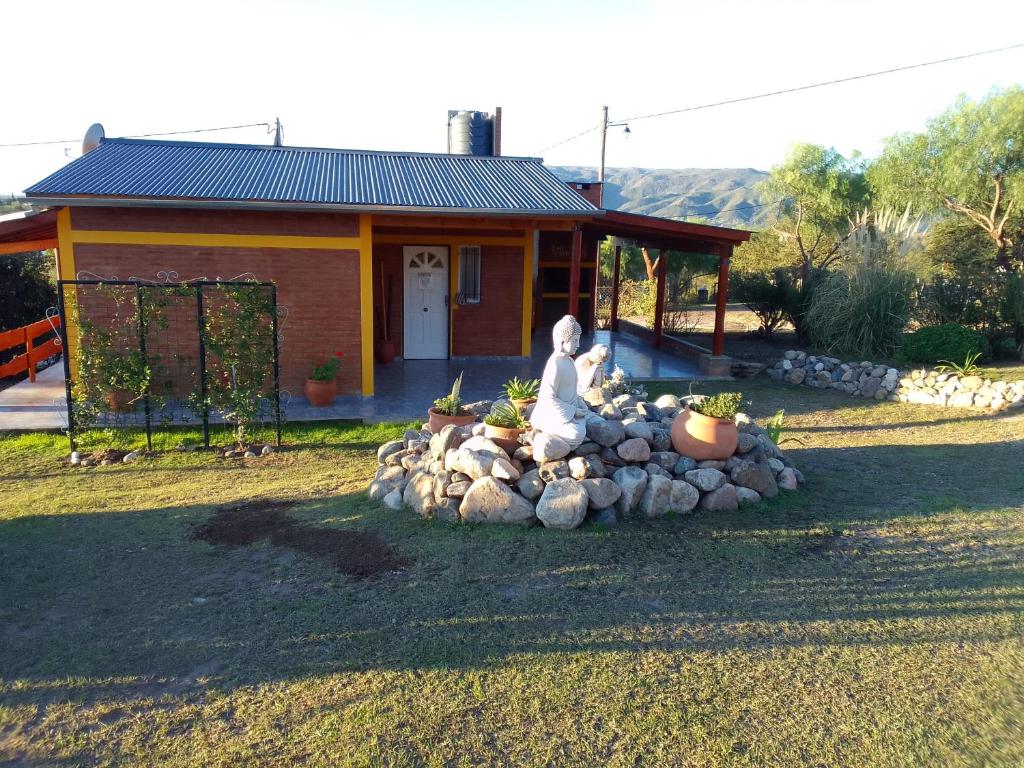 a statue sitting on a pile of rocks in front of a house at Cabañas Mi Capricho in Santa Rosa de Calamuchita