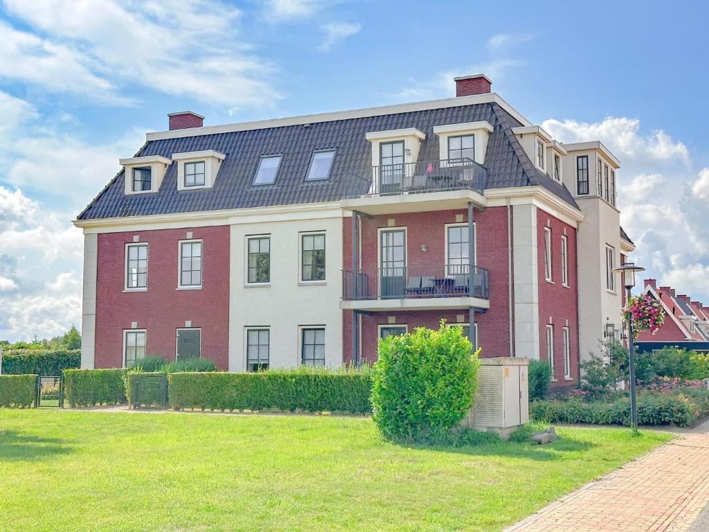 a large red and white building with a grass yard at SeaLuxe Residence in Colijnsplaat