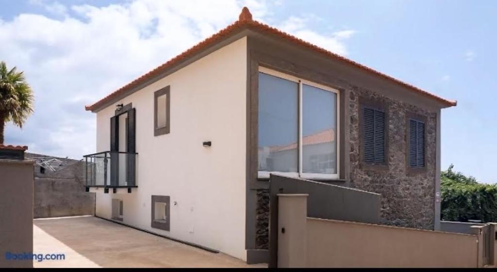 ein Haus mit einem großen Fenster an der Seite in der Unterkunft RETIRO Da CALHETA in Estreito da Calheta