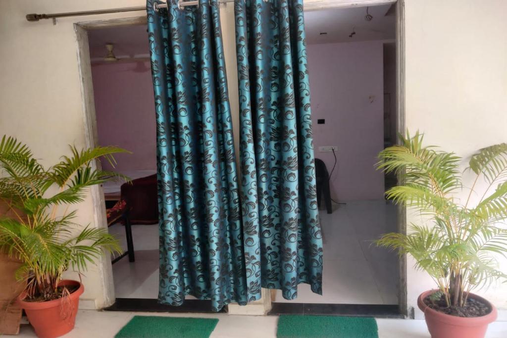 a pair of blue curtains in a room with plants at SPOT ON Sunrise Inn in Nagpur