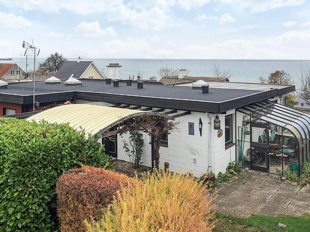 a white house with a roof with the ocean in the background at 5 person holiday home in Hesselager-By Traum in Hesselager