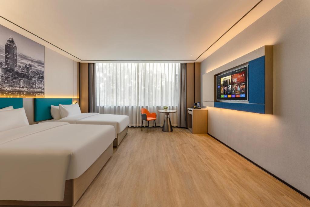 een hotelkamer met twee bedden en een tafel bij Quanli Hotel, Guangzhou Tongde Metro Station Branch in Guangzhou