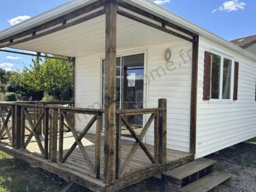 a small white cabin with a wooden deck at Mobil Home 32m² 4 pers, Terrasse à St-Sornin - API-1-52-727 in Saint-Sornin