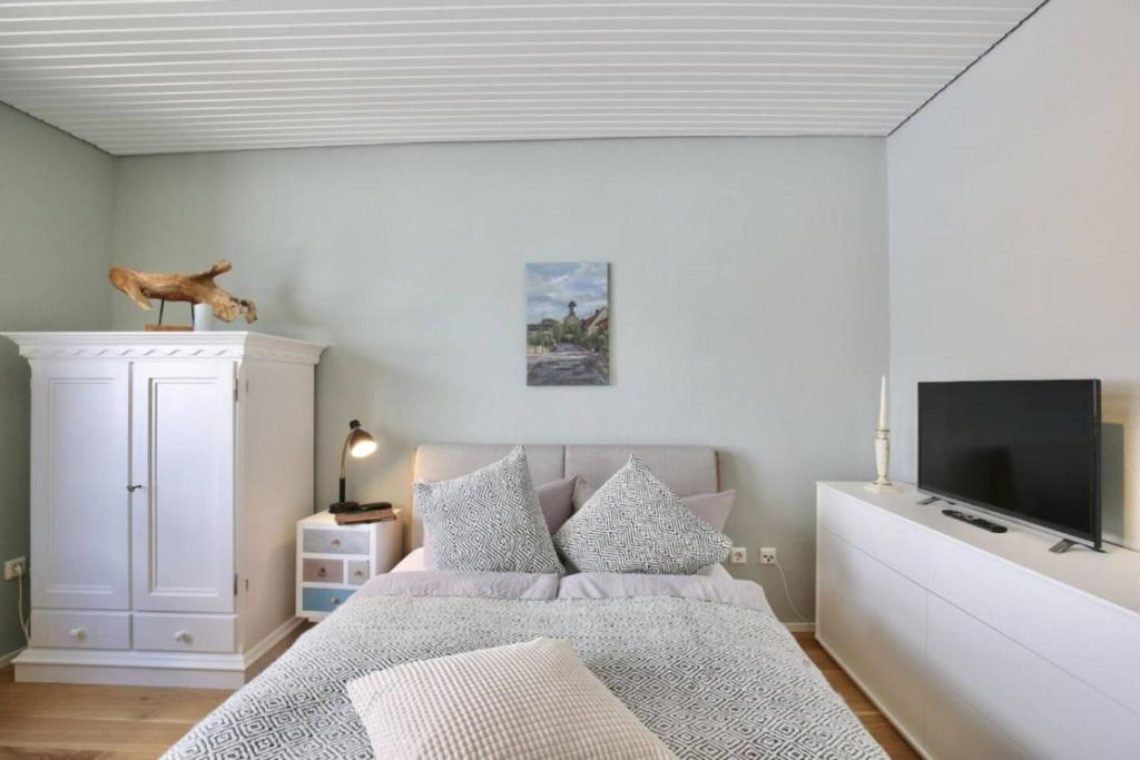 a bedroom with a bed and a flat screen tv at Lüttje Bernstein- Gemütlich Stilvoll Zentral in Wangerooge