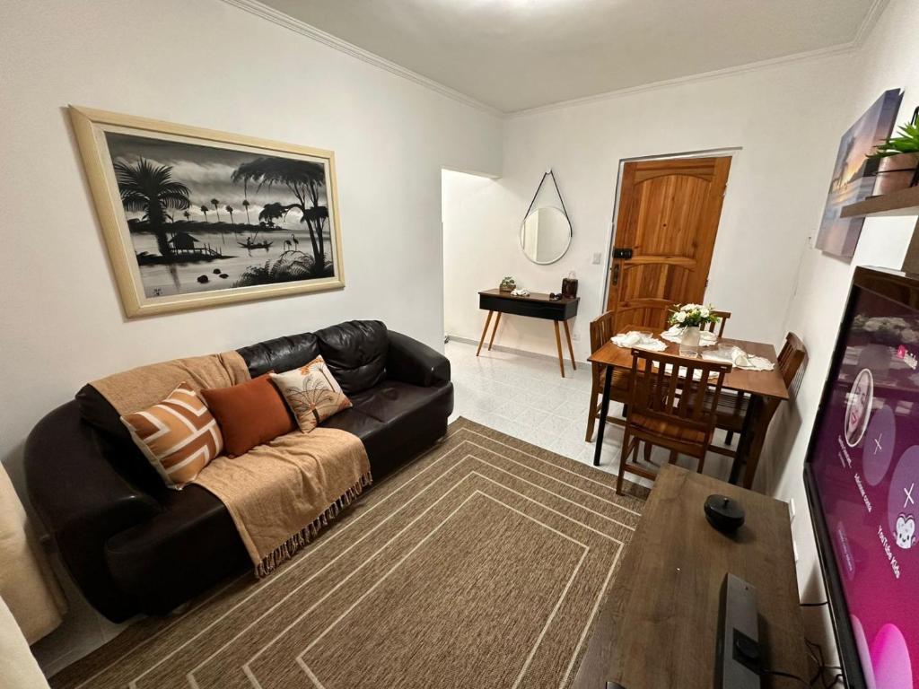 una sala de estar con un sofá y una mesa en Apê na Enseada - Ar, Wi-Fi, garagem e praia a pé!, en Guarujá