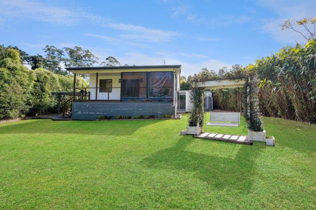 a house with a green yard with a house at Cozy Cottage at Sunshine Grove in Peachester