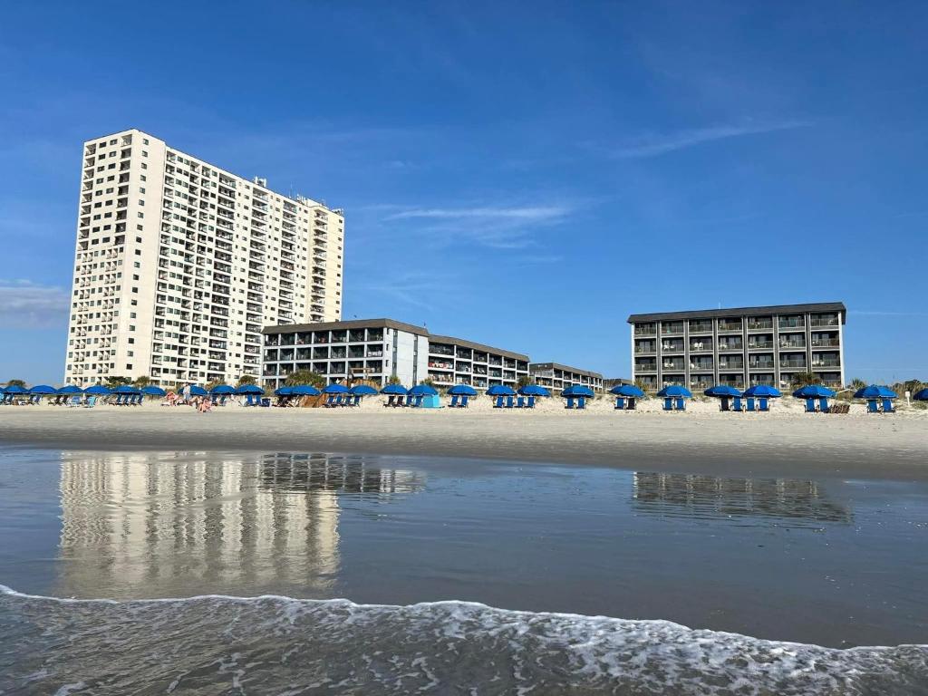 a beach with chairs and umbrellas and buildings at Myrtle Beach Resort- Unit A 428 in Myrtle Beach