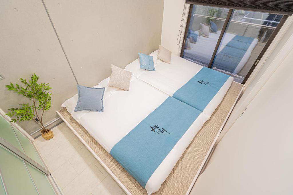 Habitación con cama con almohadas azules y ventana. en 桜の川70-36池袋駅8分钟 1DK套房 max5人房 宽敞安静 ikeburuko, en Tokio