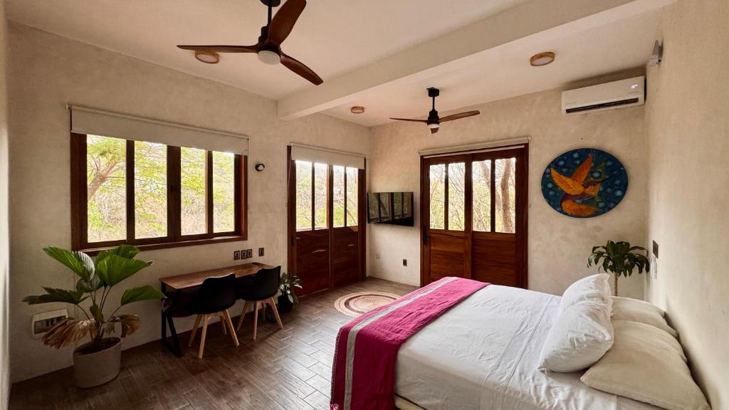 a bedroom with a bed and a table and windows at Casa Serendi in Mazunte