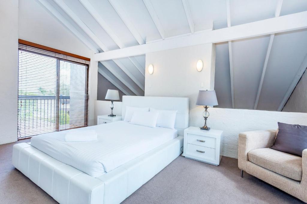 a white bedroom with a white bed and a chair at Como Mezzanine Retreat in Perth