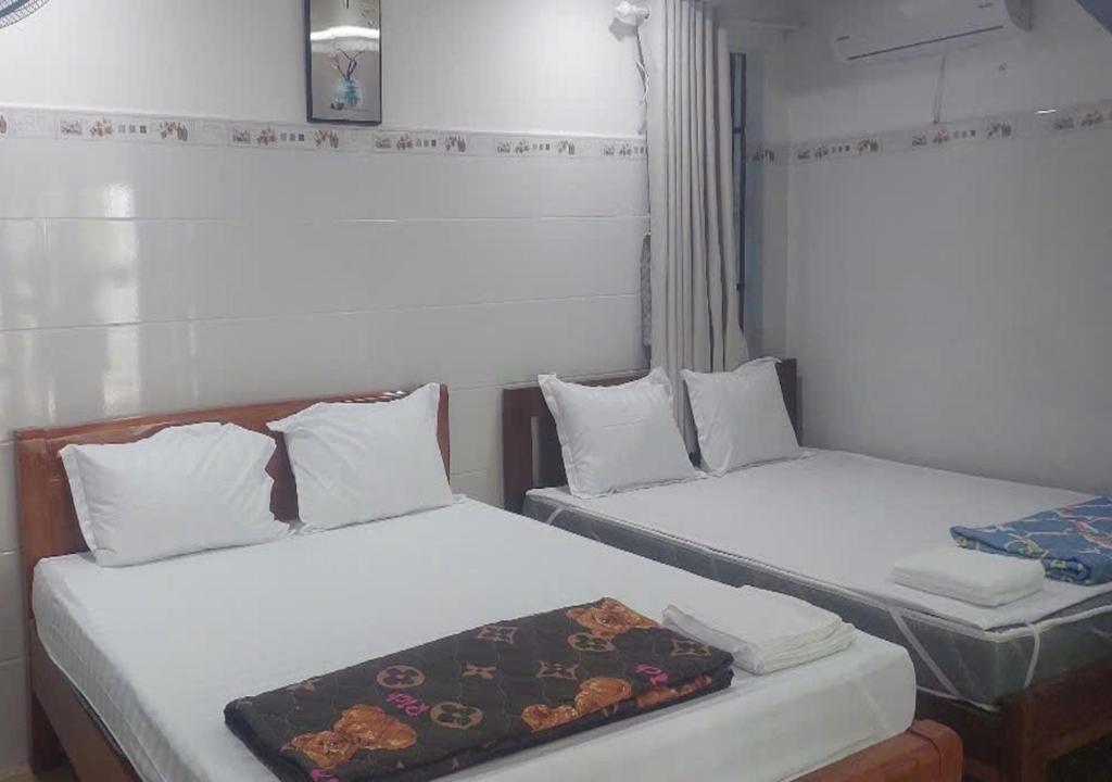 two beds in a small room with white sheets at Biển Ngọc Homestay - Ngay sát biển Phan Rang in Bắc Sớn