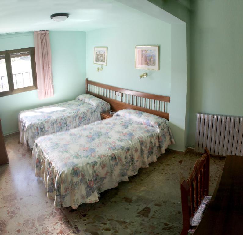 a room with two beds and a table and a window at Casa Rural Martina in Guadalaviar