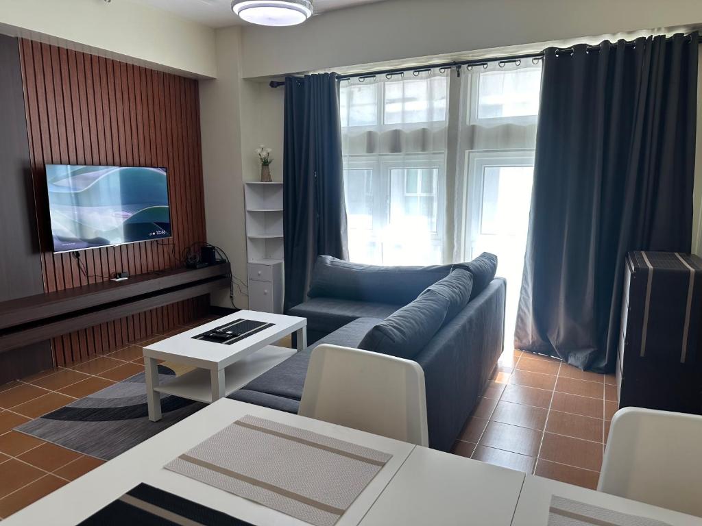 a living room with a couch and a tv at 2BR Condo in Makati- Good for 6! in Manila