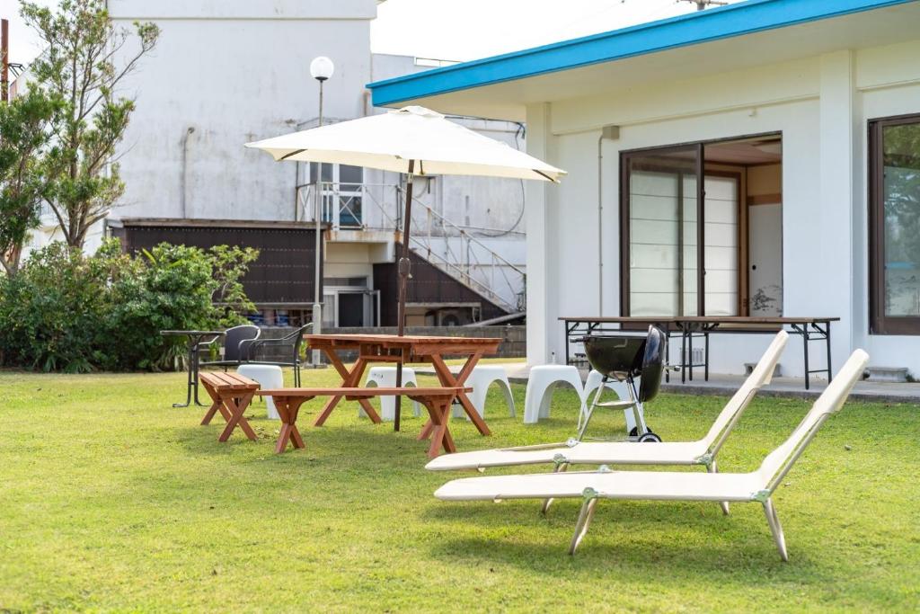 un patio avec une table, des chaises et un parasol dans l'établissement Green Beach House Iezima / Vacation STAY 8892, à Ie
