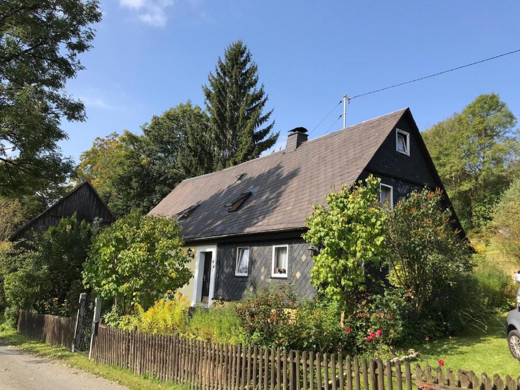 a black and white house with a fence at Ferienwohnungen Alte Schmiede in Wallenfels