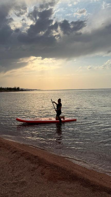 a person sitting on a paddle board in the water at Agat Lake Cottage Issyk-Kul in Tong