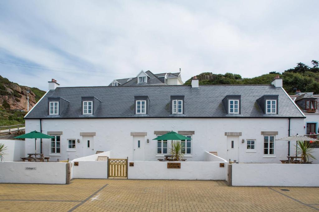 a large white building with a gray roof at La Pulente Cottages in St. Brelade
