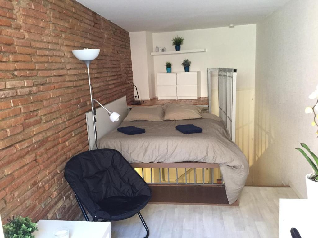 トゥールーズにあるLe petit Moulin, duplex hypercentre Toulouseのレンガの壁にベッドが備わるベッドルーム1室