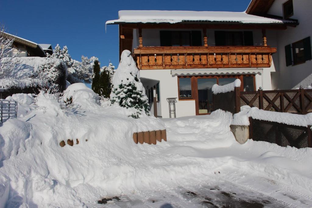 a house covered in snow in front of a house at Abendsonne in Lechbruck